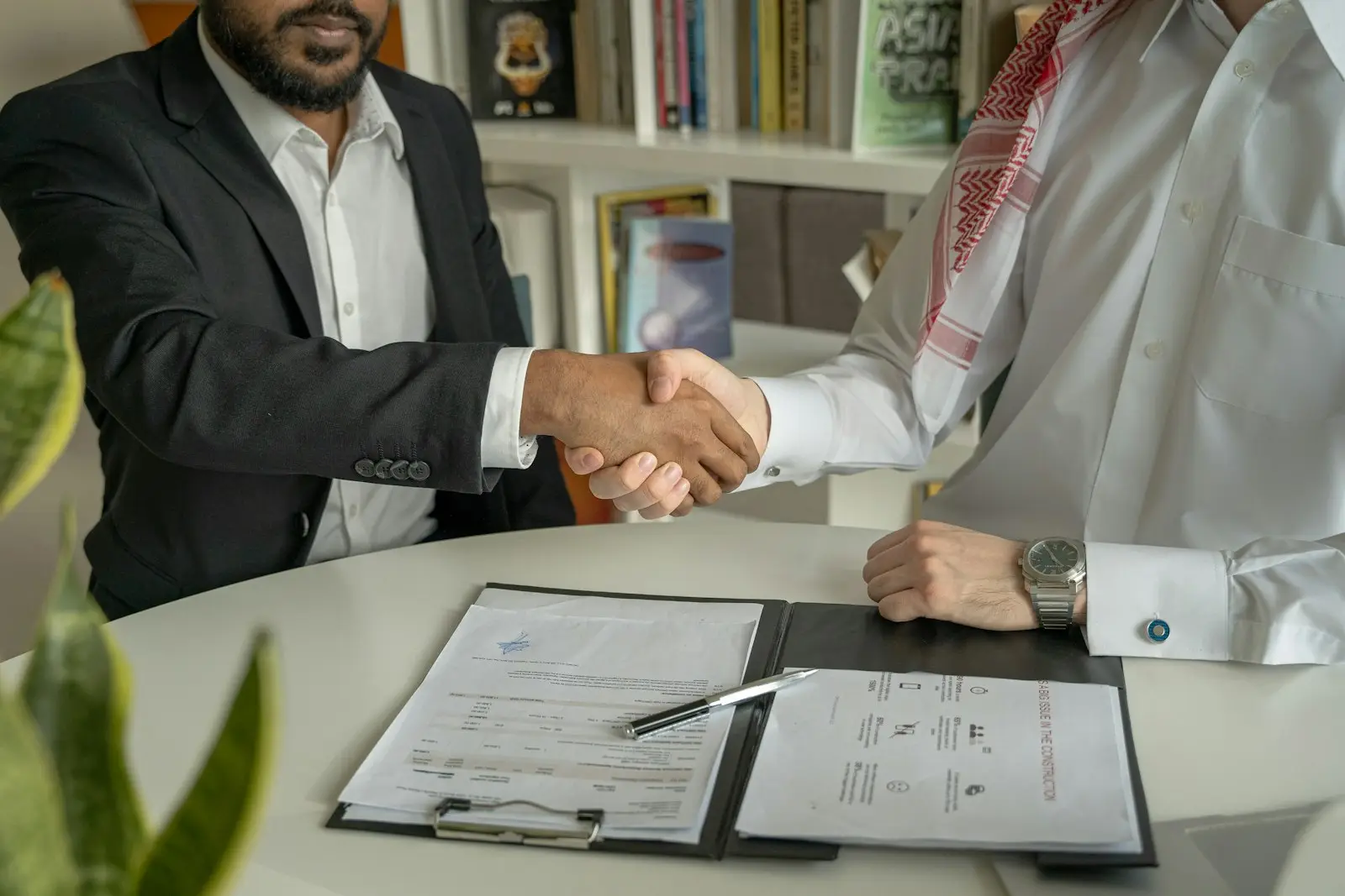 Two men shaking hands across a desk