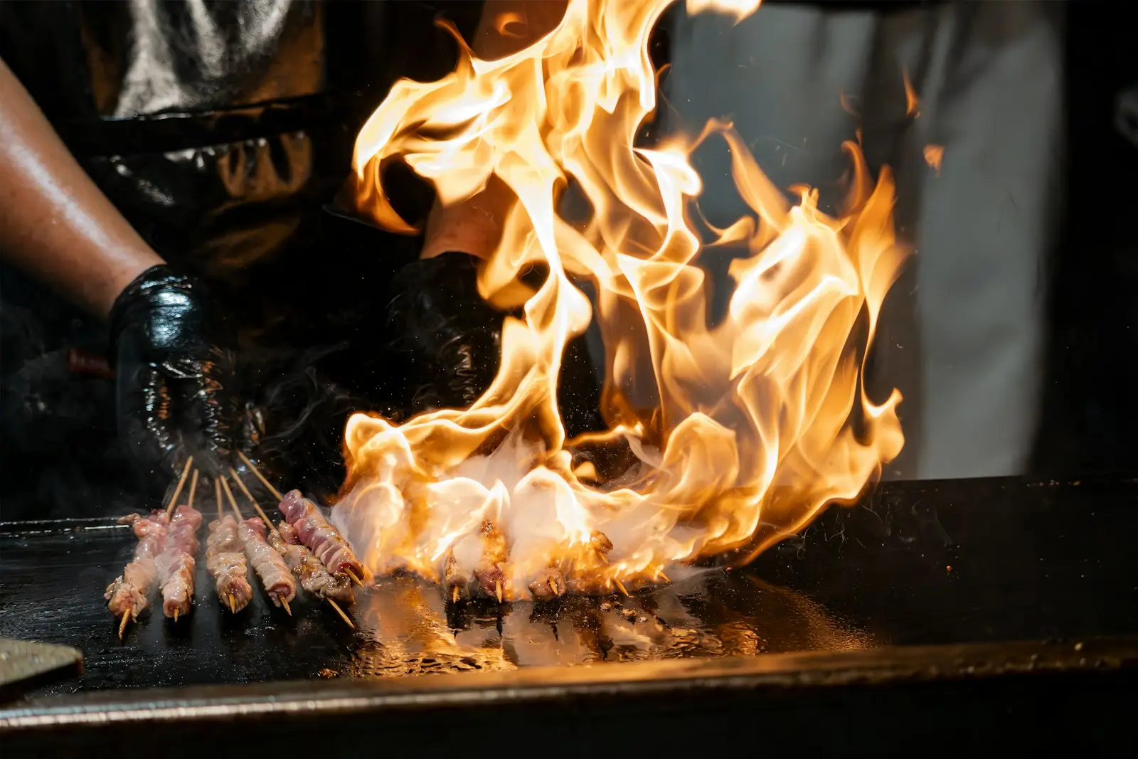 Skewers cooking over high flames in a busy kitchen