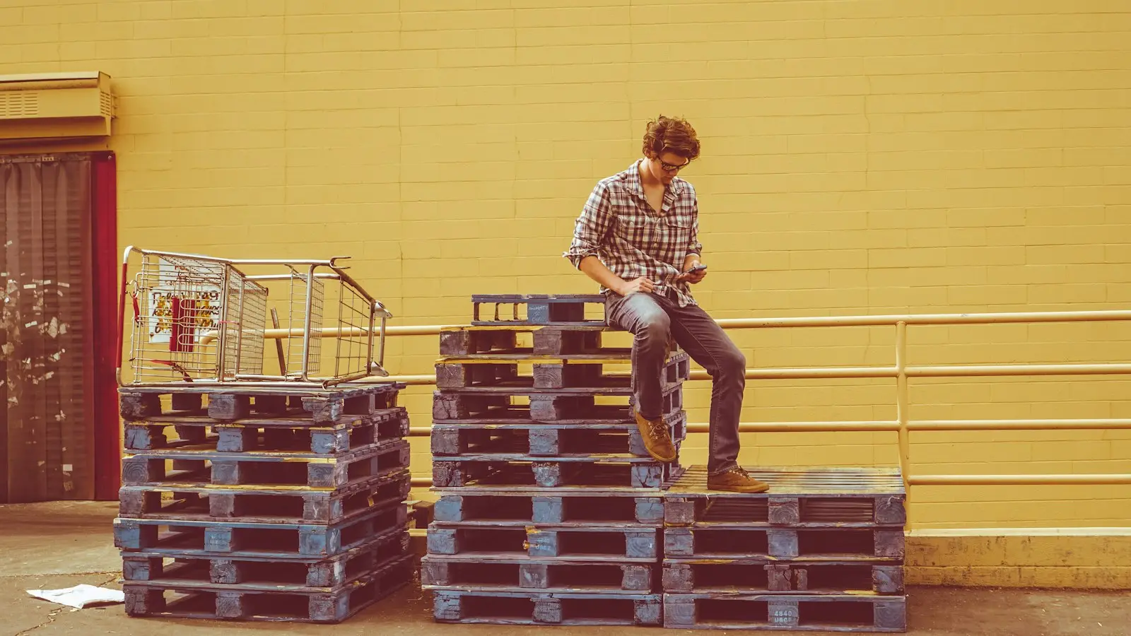 Worker sitting on a stack of pallets in a warehouse
